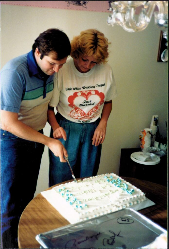 Rob and Marilyn cutting wedding cake at post-wedding party in Albany condo